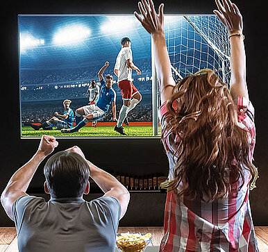 Friends cheering in front of the TV set